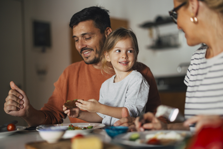 young girl smiling and sharing a meal with family