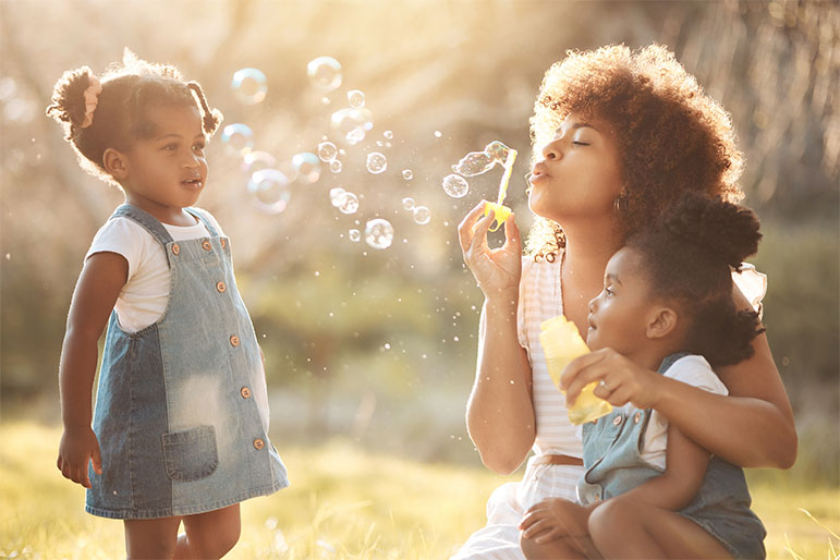 a mother blowing bubbles for her two young kids - Blue Cross Complete of Michigan Medicaid
