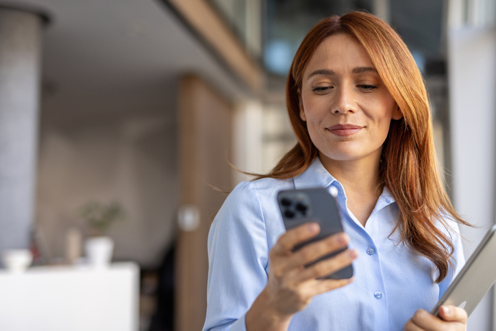 A woman smiles at information she sees on her phone