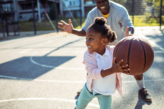 A child plays basketball with her grandfather