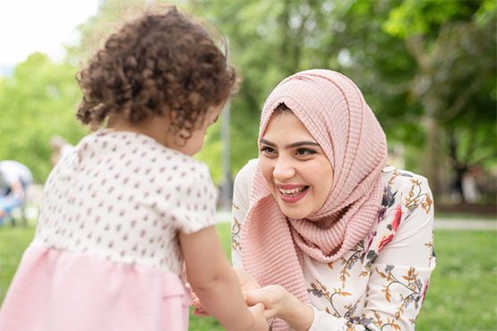 A smiling mother kneels to meet her child
