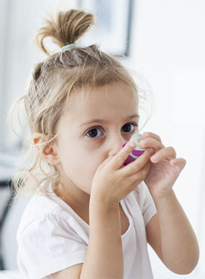 A young girl uses her inhaler