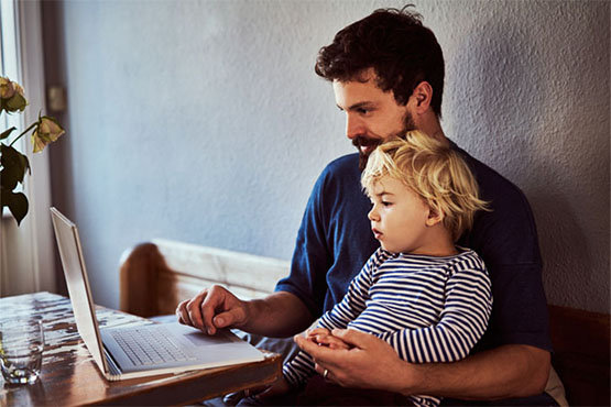 A man and young child look at a laptop screen