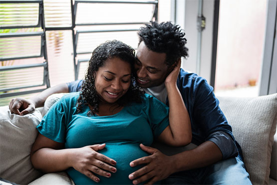 an expectant couple rest their hands on the woman's pregnant belly