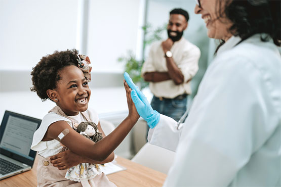 A child who just received a vaccination high fives her doctor