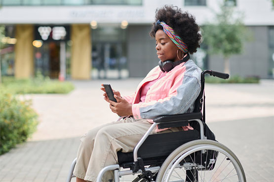 A woman using a wheelchair looks at her phone