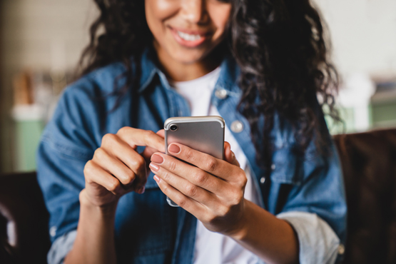 A woman smiles as she checks her phone